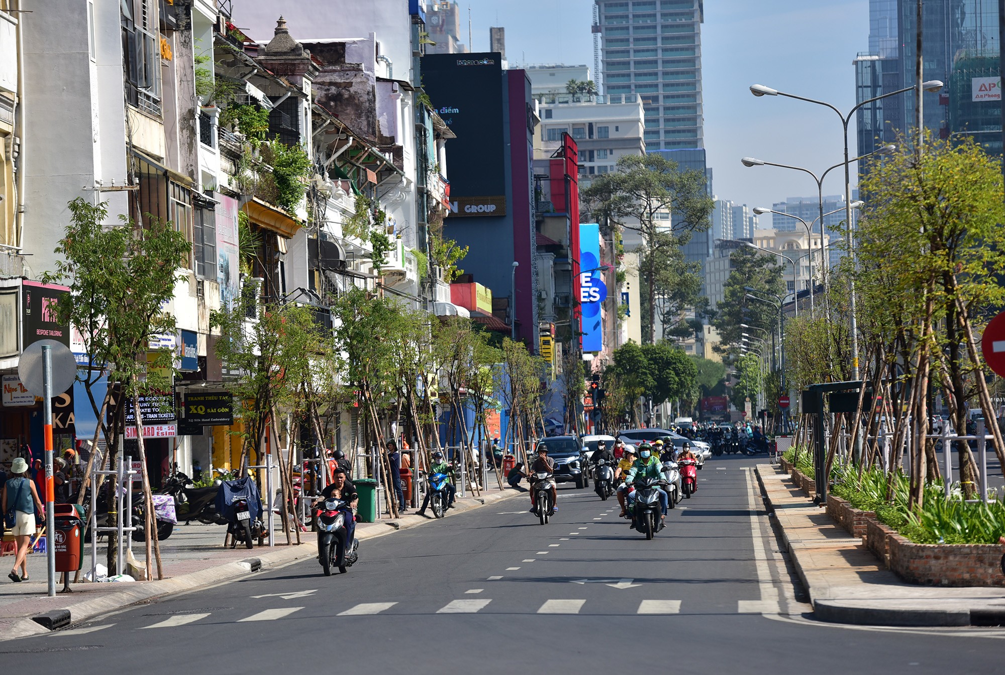 Vỉa hè, dải phân cách đường Lê Lợi hướng đi chợ Bến Thành được tạo mảng xanh mới, bóng mát với những hàng me tây vừa được trồng trong những ngày qua so với hình ảnh những mặt tiền nhà, cửa hàng cũ kỷ, trơ trọi trước đó.