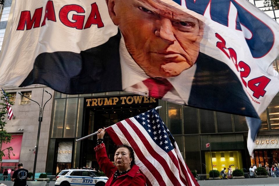 Một người ủng hộ ông Trump giương cao cờ Mỹ bên ngoài tòa Tháp Trump ở thành phố New York ngày 1/10/2023. Ảnh: Reuters