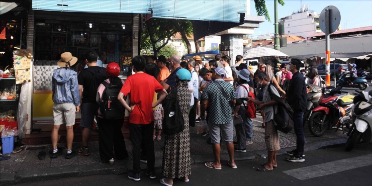 Du khách nước ngoài chờ đổi tiền trước chợ Bến Thành (quận 1).