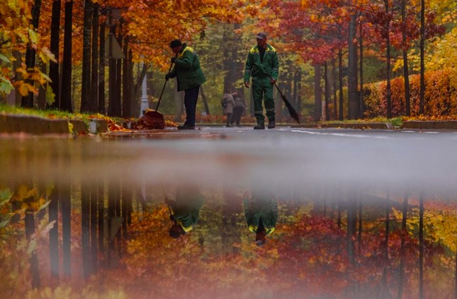 Hai công nhân môi trường quét lá trong Công viên Mátxcơva ngày 23/10. (Ảnh: Reuters)