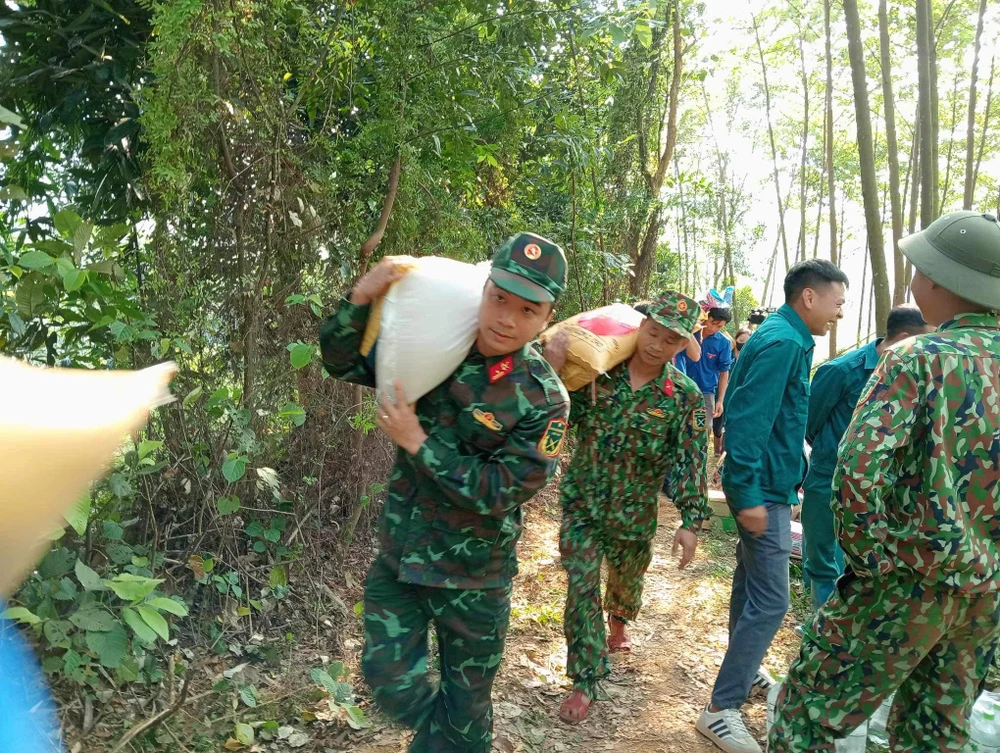 Các lực lượng vận chuyển lương thực thực phẩm thiết yếu vào hai xã Trung Sơn và Xuân An bị cô lập do sạt lở. Ảnh MẠNH CƯỜNG