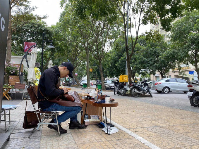 Anh Phong đánh giày trước cửa quán cafe trên phố, trong thời gian khó khăn do Covid-19 bùng phát, năm 2021. Ảnh: Khôi Nguyên