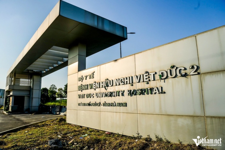 Khu vực cổng chính bệnh viện được rào chắn bằng tôn, chi tiết biển tên bệnh viện bị bung rách nham nhở.