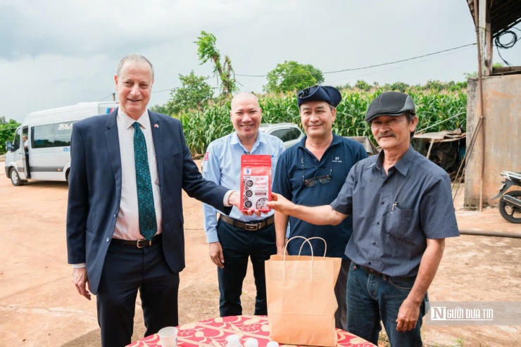 Ông Sơn (bìa phải) giới thiệu cho một vị khách nước ngoài về sản phẩm cà phê của gia đình mình.
