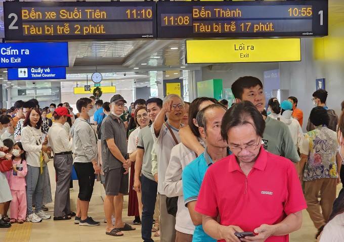 Người dân xếp hàng chờ hơn hai giờ để đi metro ở nhà ga Thảo Điền, trên bảng thông báo một số chuyến tới ga bị trễ. Ảnh: Đình Văn