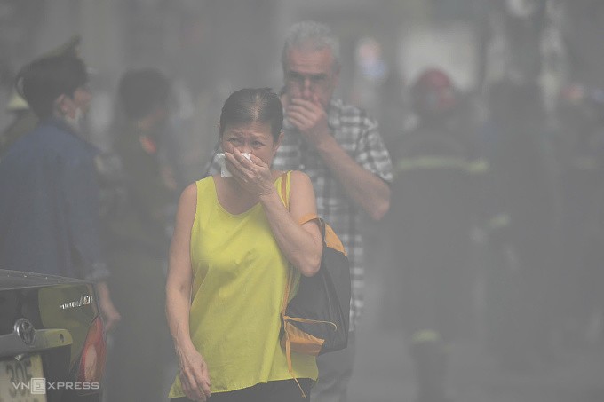 Hai khách nước ngoài bịt mũi tránh khói đen bao phủ khu vực cháy. Ảnh: Thanh Tùng