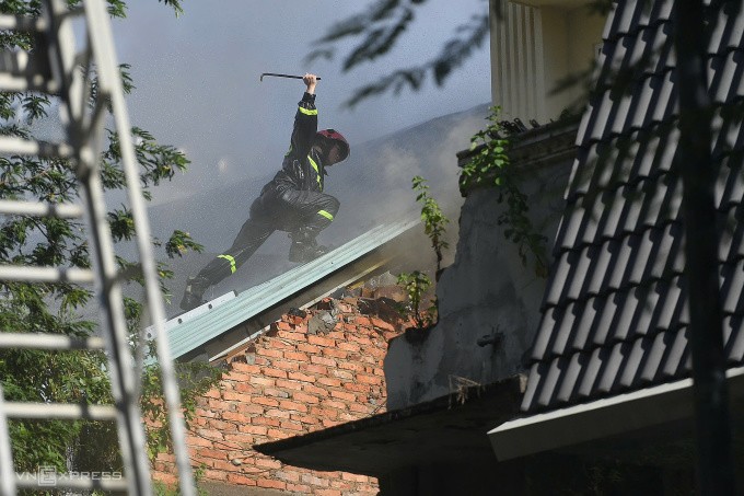 Cảnh sát phá tường và mái tôn để giải cứu người mắc kẹt. Ảnh: Thanh Tùng