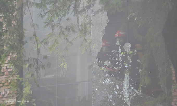 Cảnh sát phá kính nhà bên căn bên cạnh để tiếp cận ngôi nhà cháy. Ảnh: Thanh Tùng