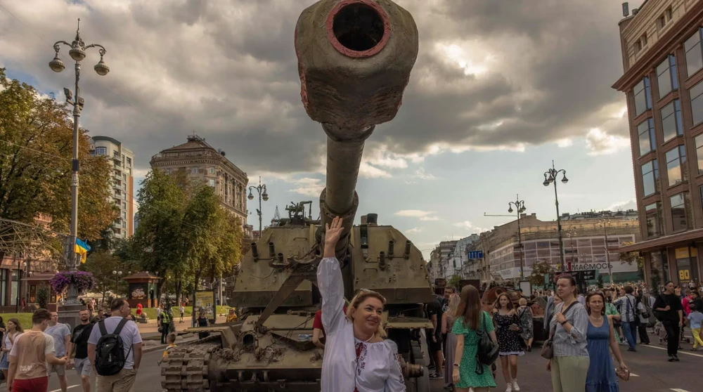 Người dân Ukraine bên xe bọc thép của Nga bị tịch thu trong chiến dịch quân sự đặc biệt và được trưng bày ở thủ đô Kiev vào tháng 8-2023. Ảnh: AFP