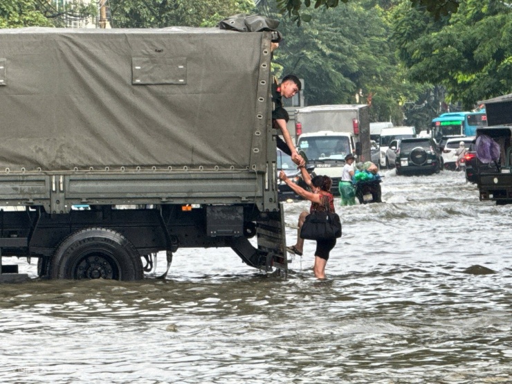 Chiến sĩ hỗ trợ người dân qua đoạn ngập sâu. Ảnh: Ngọc Thành