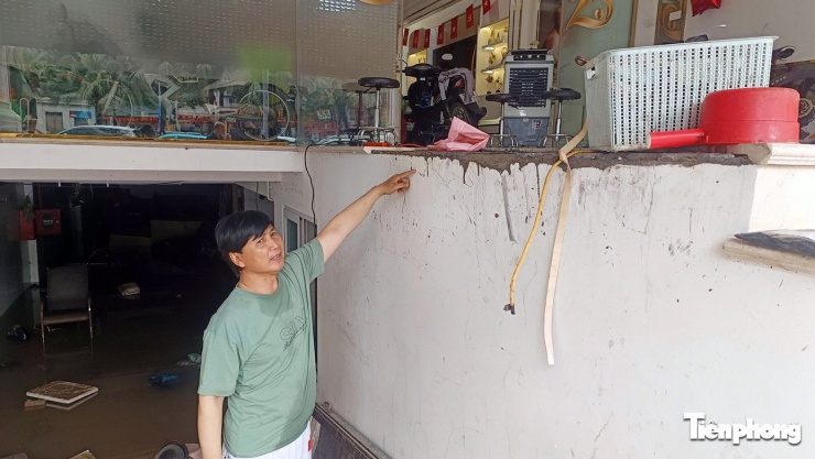 Ông Nam kể lại mực nước dâng lên ngập hầm gửi xe và khu vực ông cùng mọi người nâng xe máy lên. Ảnh: Thanh Hà