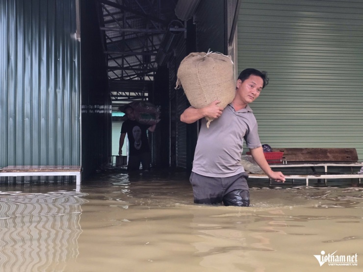 Tiểu thương phải di dời hàng hóa từ các ki-ốt ở khu vực bị ngập nặng ra ngoài.