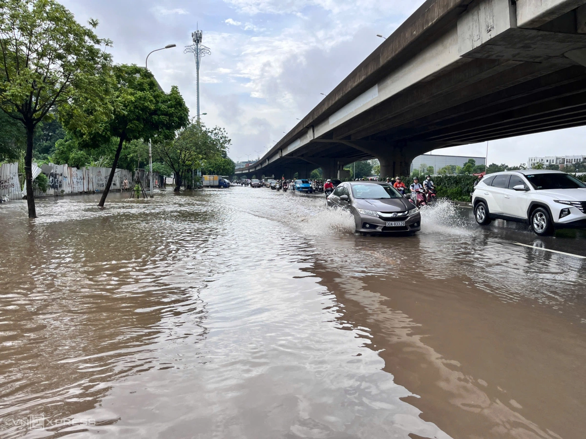Nước vẫn ngập sâu khiến dòng phương tiện phải nép sát vào lề đường. Ảnh: Huy Mạnh