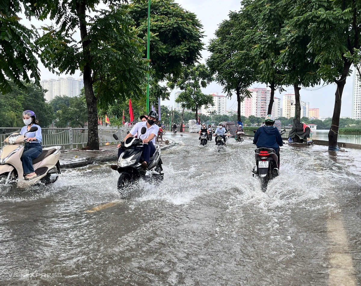 Xe máy "rẽ sóng", người co chân tránh nước ngập. Ảnh: Huy Mạnh