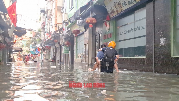 Nhiều người bị ốm hoặc bị đau chân, người thân phải cõng ra khỏi nơi ngập. Ảnh: Văn Duẩn