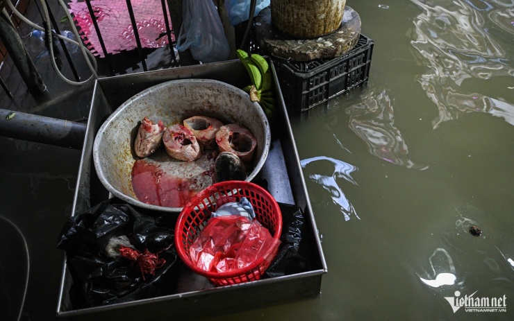 Chị T. vẫn ngâm mình trong nước để cố gắng bán nốt chỗ cá đã nhập về. Ảnh: Huy Nguyễn