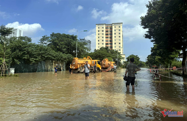 Nước ngập khắp nơi, người dân bì bõm lội nước đưa con đến lớp.