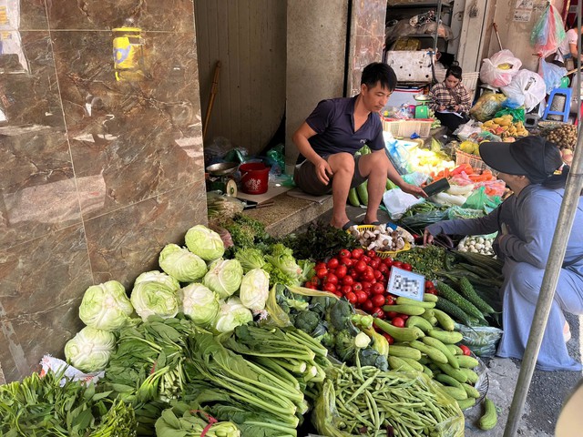 Theo tiểu thương chia sẻ, rau xanh bị dập nát do ngập úng, tiểu thương phải lựa chọn kỹ mới có thể bày bán. Ảnh: Đan Tâm.