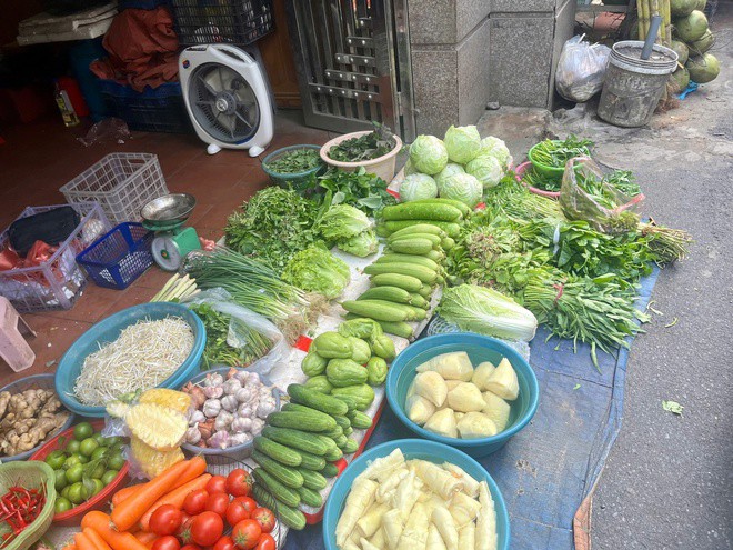 Chị Nhung (tiểu thương tại chợ Đình Thôn) chia sẻ, rau ngập úng gặp nắng dễ thối hỏng, có thể khiến giá tiếp tục tăng. Ảnh: Đan Tâm.