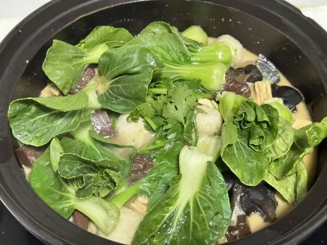 Cuối cùng, cho rau xanh và ít ngò vào, đun sôi trở lại.