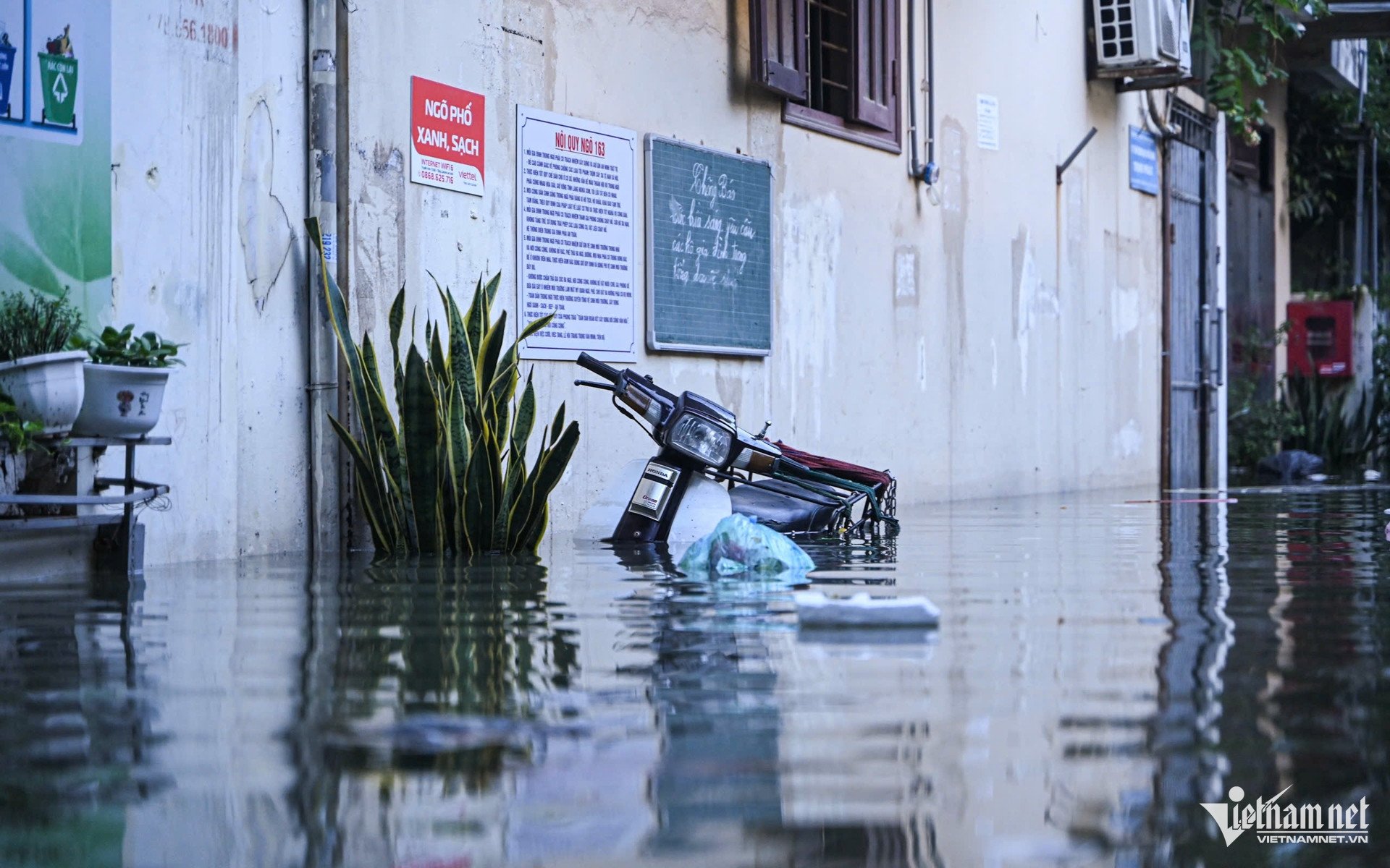 Xe máy đã được kéo tới chỗ cao nhưng vẫn "chìm nổi" trong biển nước. Ảnh: Huy Nguyễn