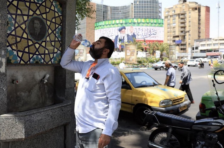 Một người Iran uống nước từ vòi công cộng giữa lúc trời nóng 40°C. Ảnh: EPA