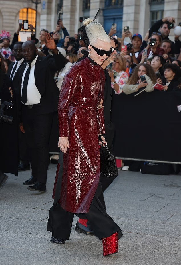 Nhà thiết kế Daphne Guinness thể hiện phong cách thời trang độc đáo với áo khoác da rắn màu đỏ cùng đôi giày cao gót đế xuồng.