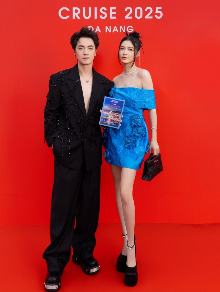 Ở show thời trang của Vũ Ngọc và Son, Thủy Anh chọn váy ngắn xanh dương đính hoa 3D. Để phù hợp với bộ cánh của chồng, cô phối giày platform của Versace và túi Kelly đen.