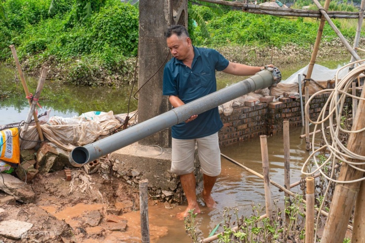 Ông Nguyễn Đình Thắng tháo bỏ chiếc máy bơm bị hỏng do nước dâng cao. Gia đình ông có khoảng 3.600 m2 hoa bị chết, chủ yếu là cúc vàng, hoa hồng và hoa ly, thiệt hại ước tính 150 triệu đồng.