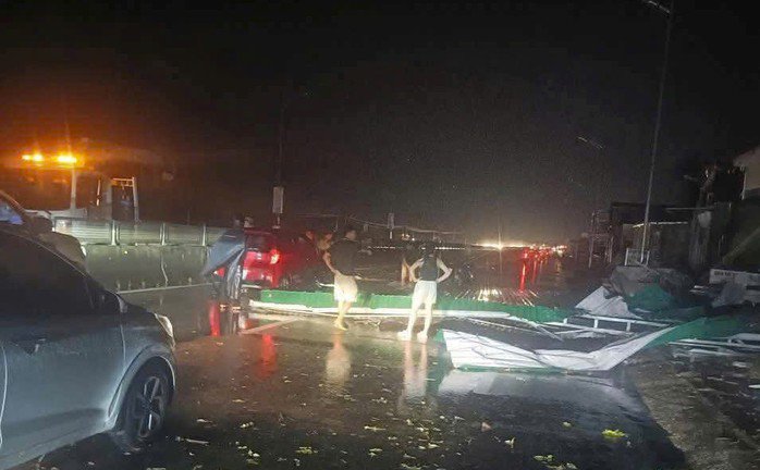 Một tấm tôn lớn bị gió cuốn bay rơi trúng xe ô tô lưu thông trên quốc lộ đoạn qua xã Nghi Lộc. Ảnh: N.Lộc