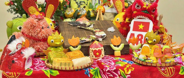 Xung quanh mâm cỗ Trung thu là bánh nướng, bánh dẻo, đèn lồng, lân sư cùng các hình con thú tạo từ hoa quả như thỏ bưởi, chim hồng đeo nơ lá cờ Tổ quốc – tất cả hòa quyện tạo nên một không gian đậm sắc màu truyền thống. Ảnh NVCC