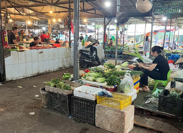 Tiểu thương tại chợ tạm Nam Trung Yên kê hàng lên cao, thu hẹp diện tích bày bán để đề phòng ngập. Ảnh: Đan Tâm.