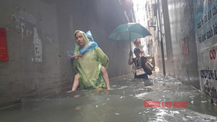 Một gia đình ở TDP số 3, bố cõng con, mẹ tay xách nách mang những vật dụng cần thiết và "di tản" khỏi nhà. Ảnh: Văn Duẩn