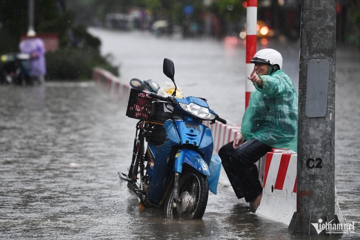 Một người phụ nữ làm nghề chở hàng sau khi đẩy xe máy được 2 km liền ngồi nghỉ vì quá mệt tại dải phân cách ở ngã tư Nguyễn Hoàng - Lê Đức Thọ.