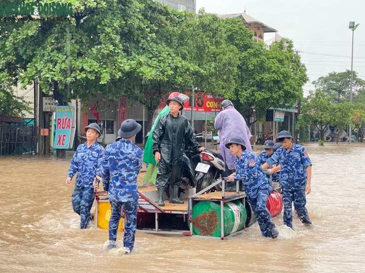 Trong mưa lạnh và nước ngập, nhiều chiến sĩ Cảnh sát biển Việt Nam dầm mình hỗ trợ người dân vận chuyển người và xe máy qua điểm ngập.
