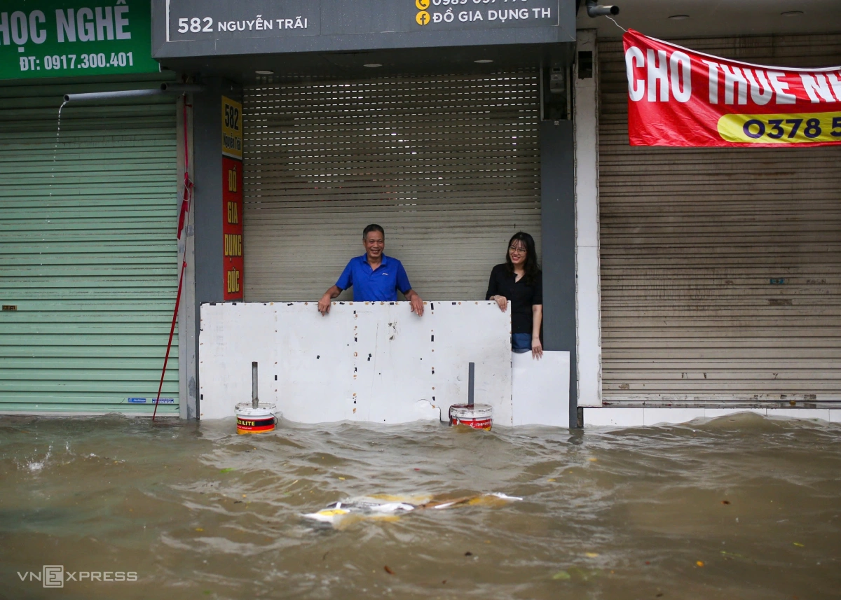 Từ 4h sáng, nhiều hộ kinh doanh đã phải dậy sớm, căng bạt, be bờ để tránh nước tràn vào bên trong cửa hàng. Ảnh: Phạm Chiểu