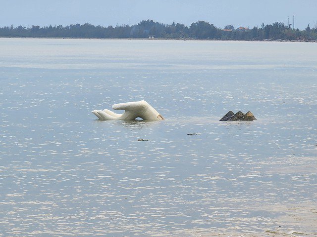 Tượng cánh tay bị sóng đánh nghiêng ngả.