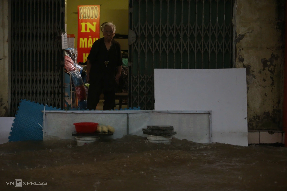 Người dân trên đường Nguyễn Trãi dùng bạt chắn nước tràn vào nhà. Ảnh: Phạm Chiểu