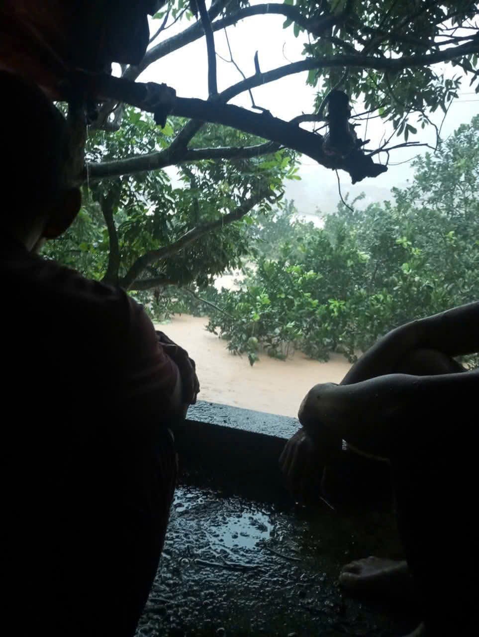 Bố mẹ và chồng chị Huệ đang ngồi trên mái nhà hàng xóm, không mang theo được bất cứ vật dụng nào.