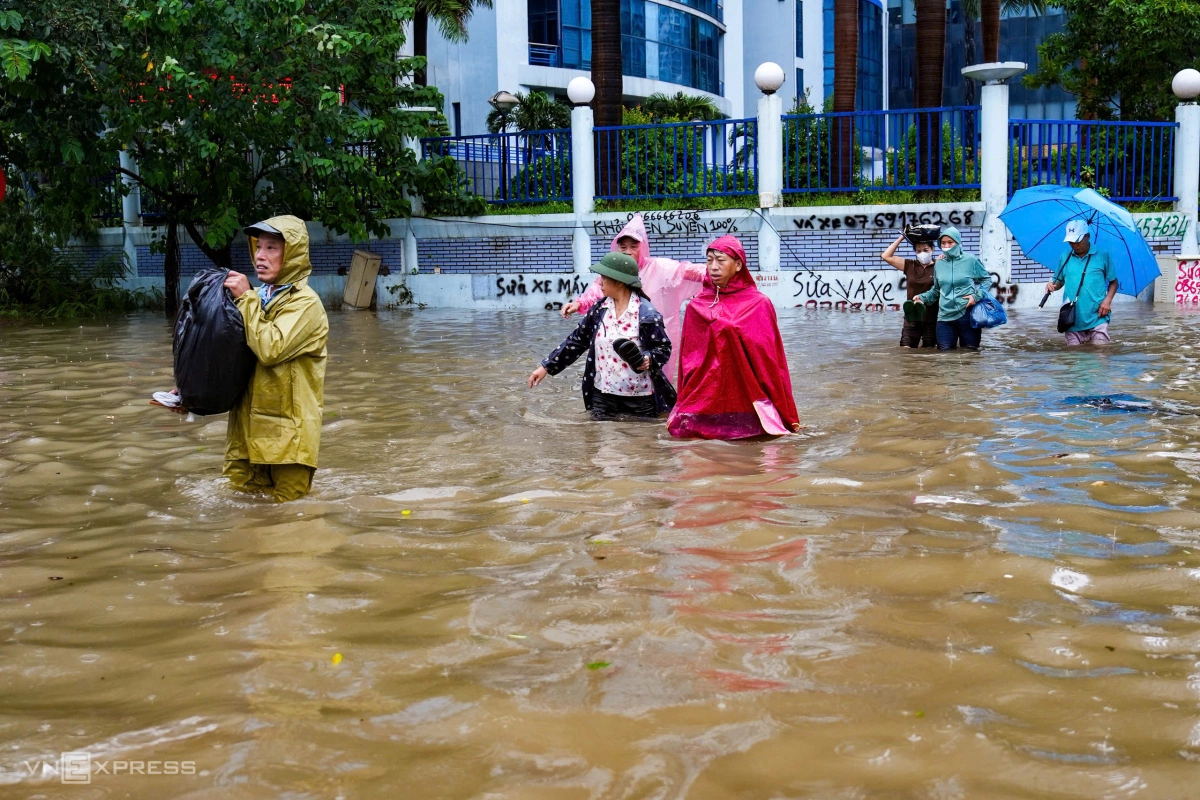 Người dân xách đồ lội bộ trong nước trên phố Phạm Hùng về bến xe Mỹ Đình. Ảnh: Tùng Đinh