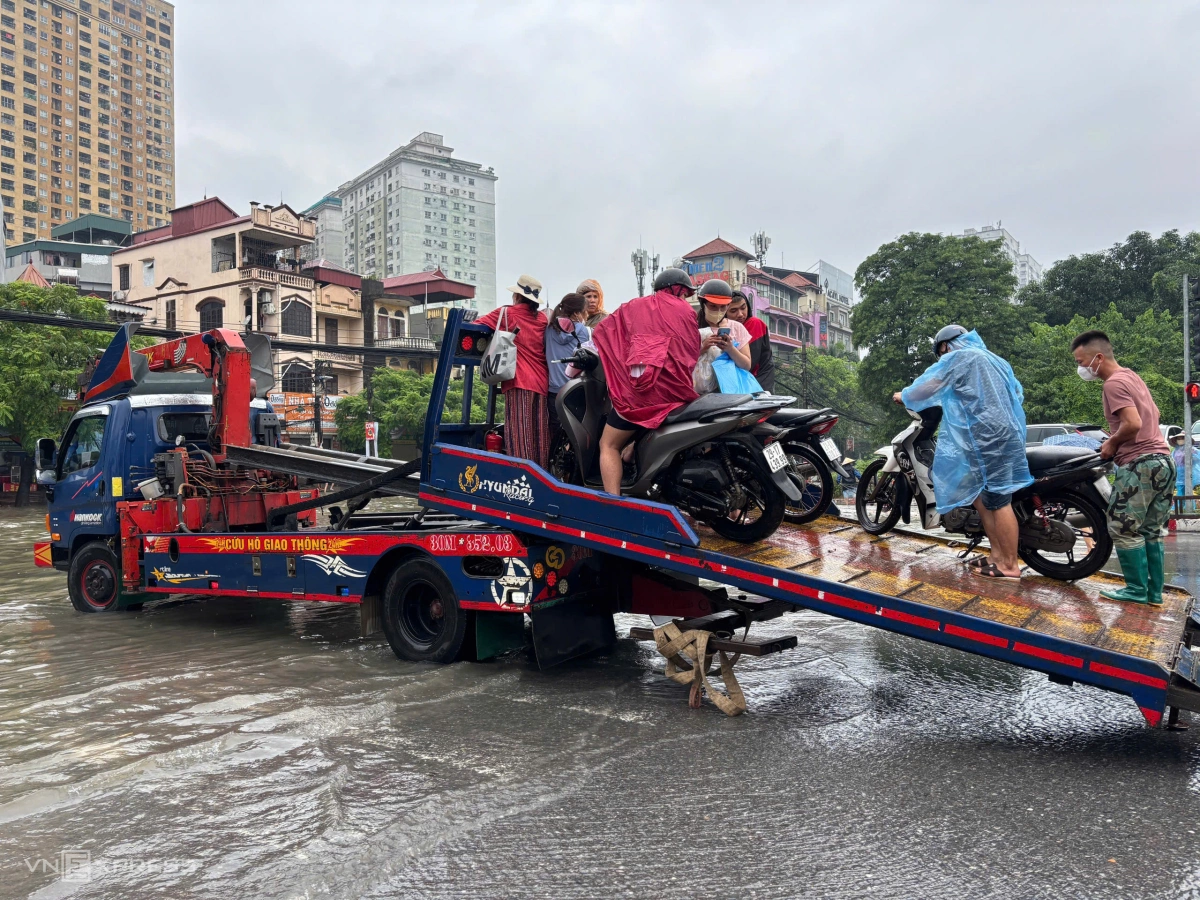 Anh Nguyễn Duy Khánh cùng các đồng nghiệp hỗ trợ xe máy đi qua đoạn đường ngập sâu trên đường Phùng Hưng, phường Hà Đông. Ảnh: Huy Mạnh