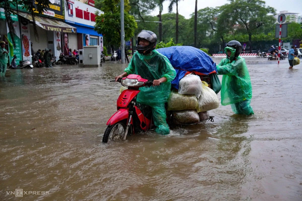 Tiểu thương đẩy xe qua đoạn ngập trước làng Phú Mỹ. Ảnh: Lộc Chung