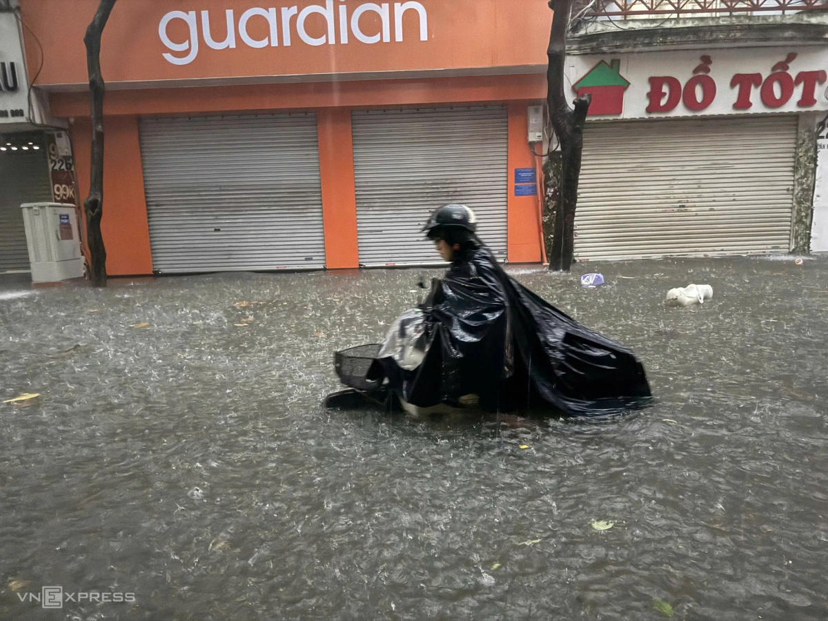 Nước ngập hết bánh xe máy, người dân phải xuống dắt bộ. Ảnh: Lộc Chung