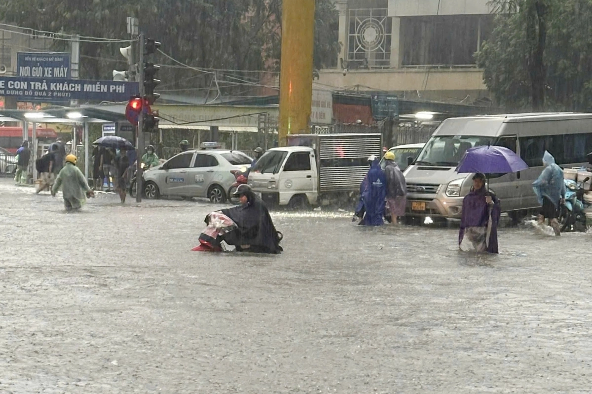 Người dân vất vả tìm chỗ cao để di chuyển trên đường. Ảnh: Vũ Ngân