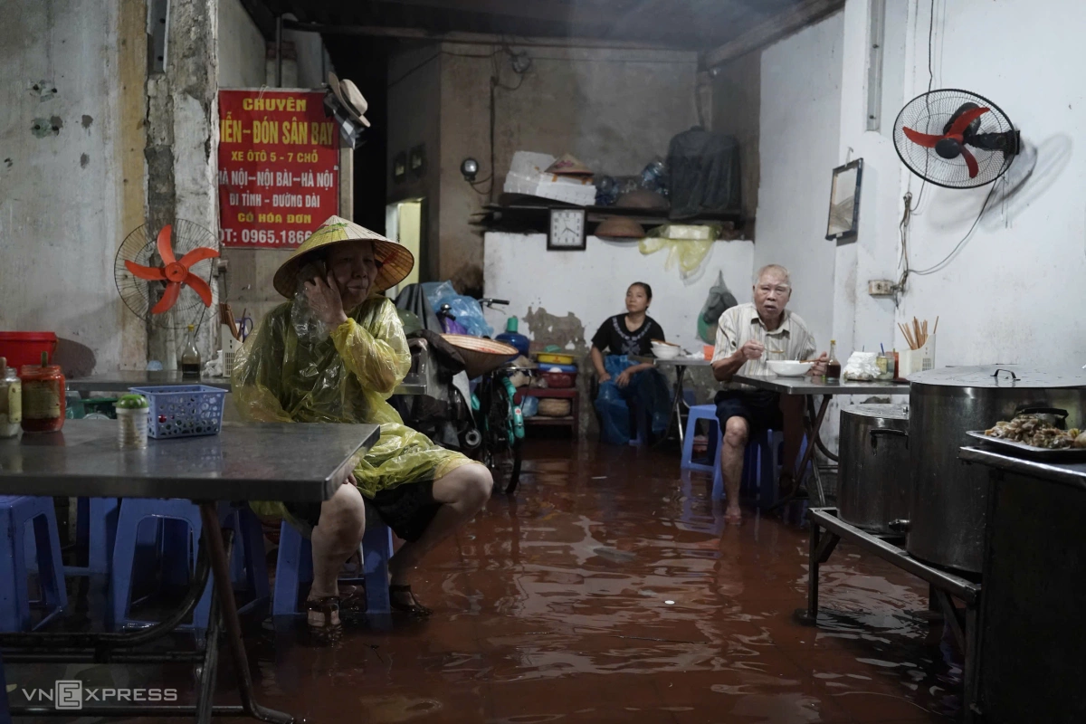 Người dân đội nón, trùm áo mưa để ăn sáng. Ảnh: Hoàng Giang