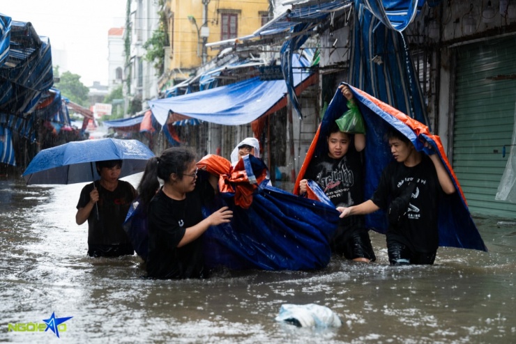 Nhóm tiểu thương dùng bạt làm 'thuyền' vận chuyển hàng hóa trong nước ngập.