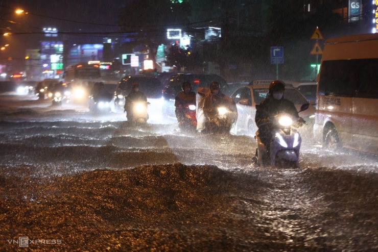 Tại đường Đỗ Xuân Hợp, nước dâng cao lút bánh xe khiến nhiều người chật vật đi lại.