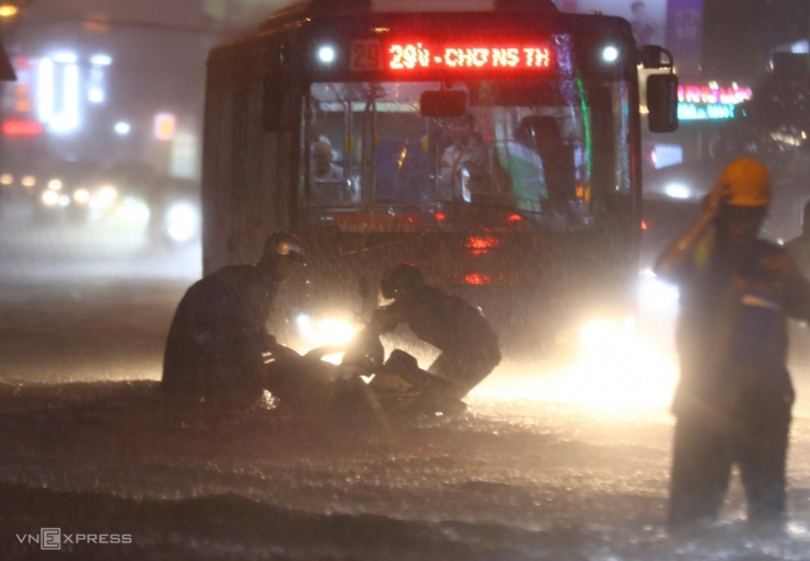 Xe máy bị sóng đánh ngã ngay đầu ôtô buýt, người đi đường gần đó chạy lại hỗ trợ tránh va chạm giao thông.