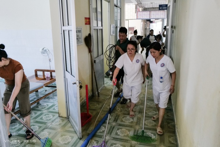Bác sĩ, nhân viên y tế cùng người dân đẩy bùn đất ra khỏi hành lang, phòng khám bệnh.