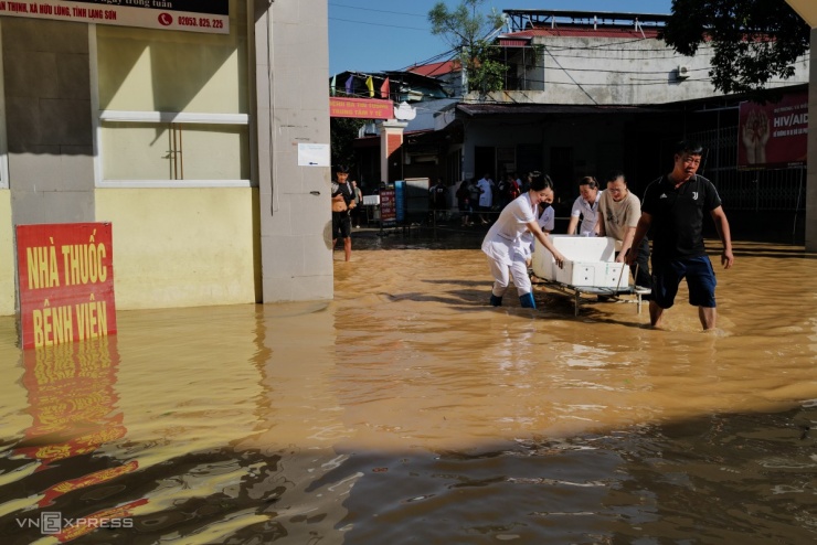Sáng nay, sân bệnh viện vẫn ngập khoảng 0,5 m, nhân viên y tế và người dân phải dùng thùng xốp tự chế để chuyển thực phẩm vào trong. Toàn bộ thuốc, vật tư y tế được chuyển vào bằng thuyền.